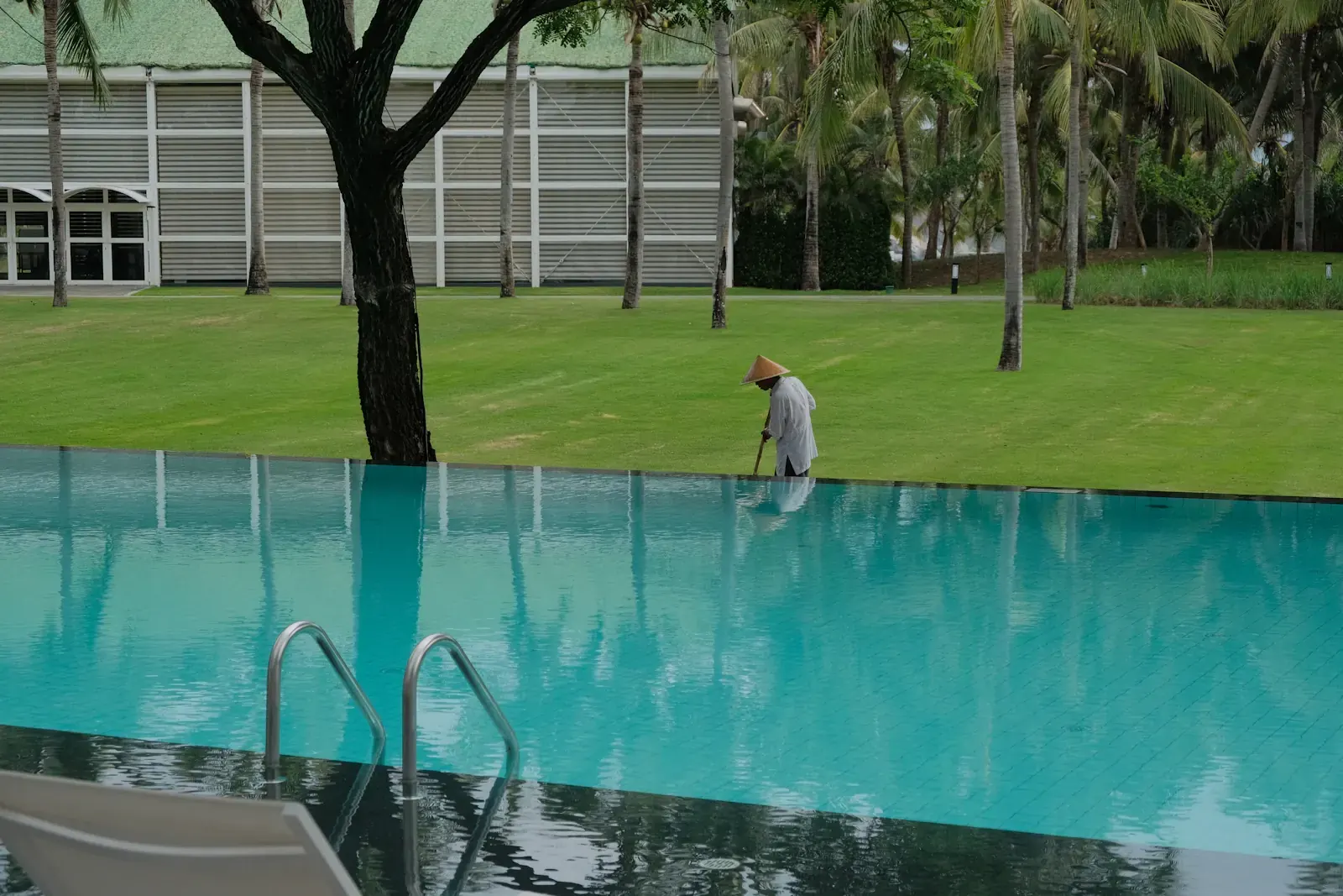 An attendant cleans the edge of a resort pool