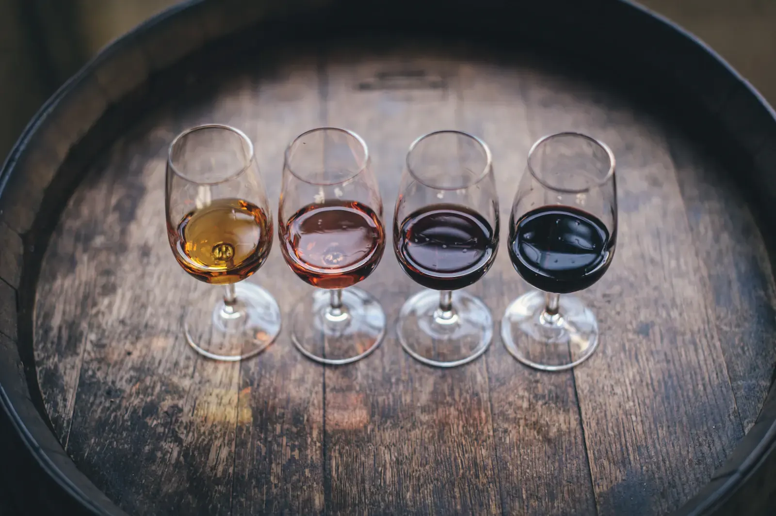 A tasting flight of four wines set on a barrel