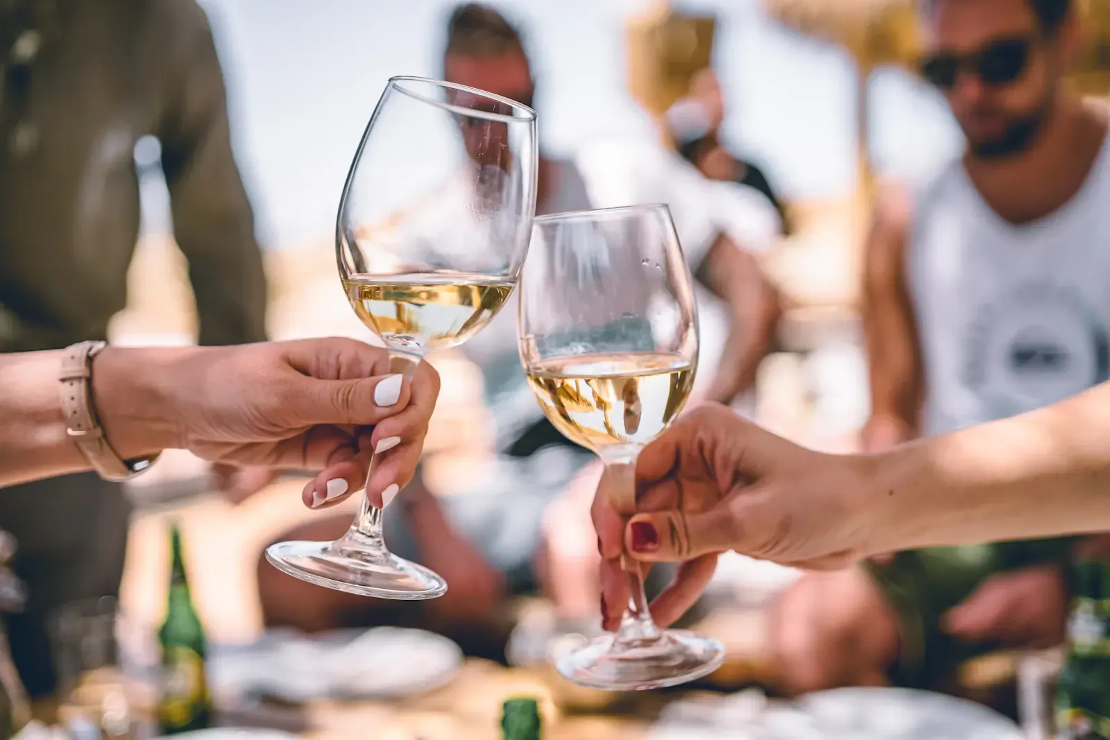 Friends raise glasses of white wine outdoors