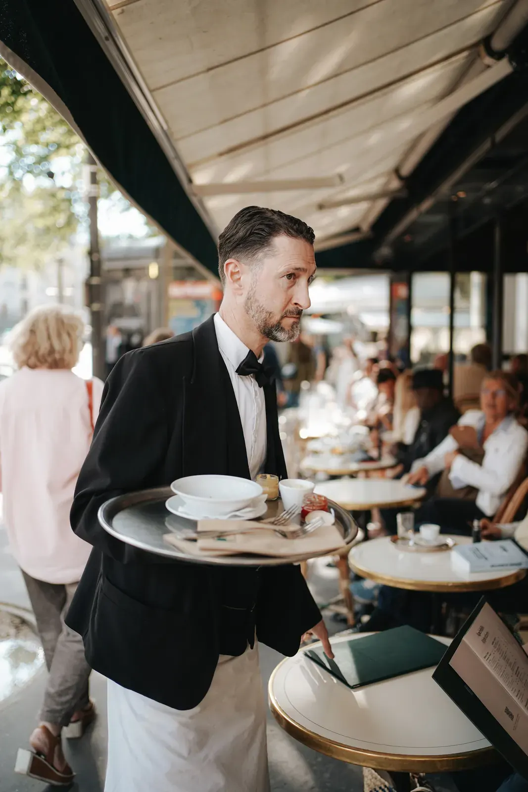 A waiter in a tuxedo carries plates through a dining room